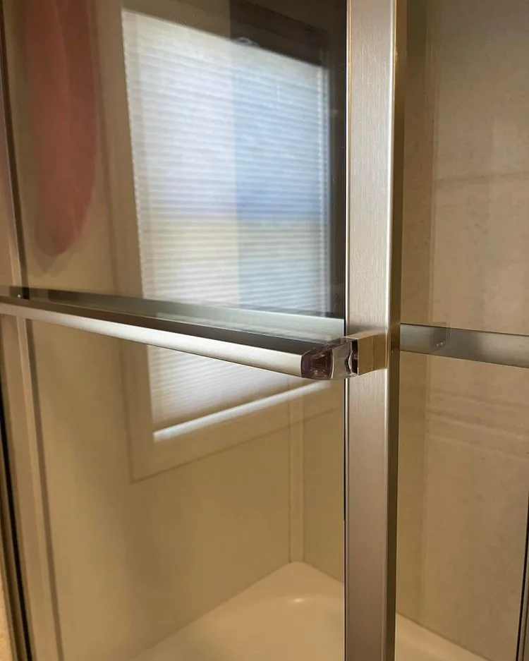 A glass shower door and track with the film removed